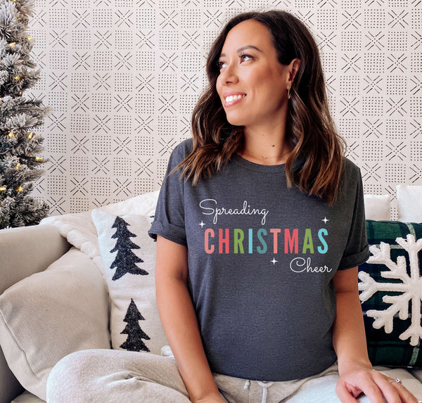Woman wearing a holiday graphic tee that says "Spreading Christmas Cheer".