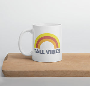 White, ceramic 11 oz coffee mug with a rainbow and the phrase "Tall Vibes"